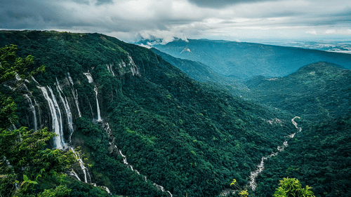 an aerial view of the many waterfalls cascading down from a mountain side in Cherrapunjee