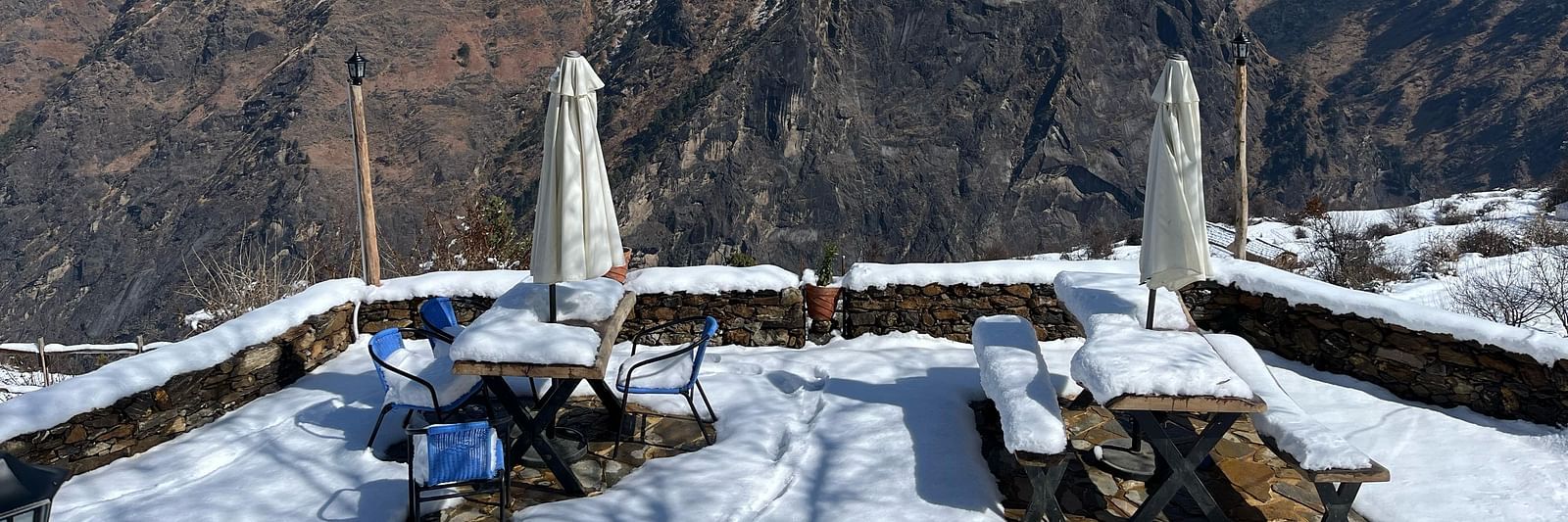 Image of outdoor seating area filled with snow and mountains in the background | Faraway Cottages, Auli