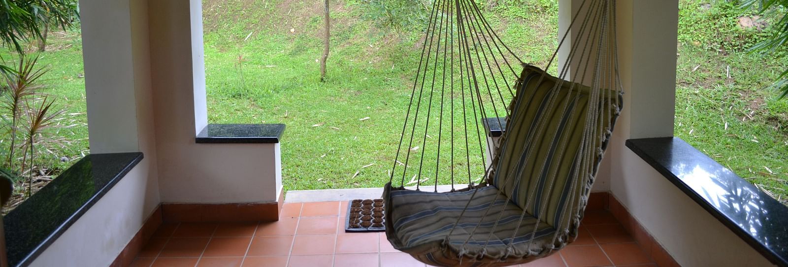 a cot inside a small shed with gardens outside - Kadkani River Resort, Coorg
