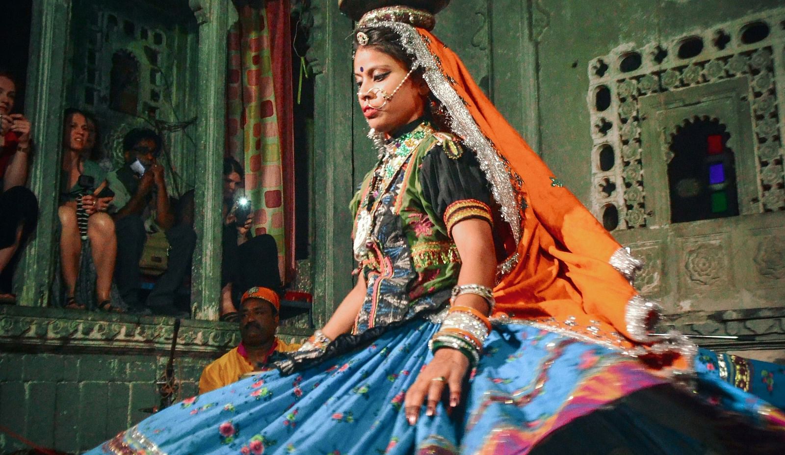 A woman performing at Bagore Ki Haveli with people looking on in the background