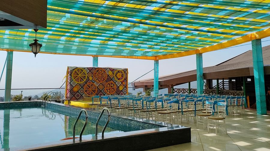 Seating arrangement made near swimming pool at The Grand Legacy Resort & Spa featuring several chairs and a stage decorated with large fabric pieces and flowers