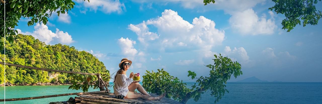 Woman traveller with scenic ocean and trees background and the text, Indulge in Paradise.