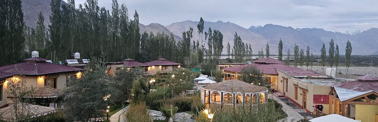 Panoramic view of White Sands Resort, Ladakh surrounded by lush greenery and mountain views.