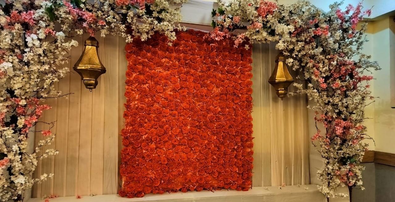 Decorative stage with red floral wall and flower arrangements at Max Hotel Prayagraj.