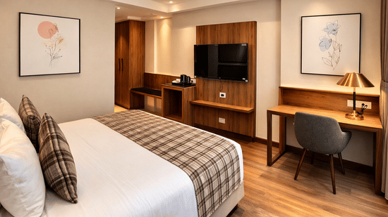 Bedroom at Pride Premier Darjeeling featuring a bed, a flat TV screen mounted on the wall, work desk and chair, and tea and coffee maker.