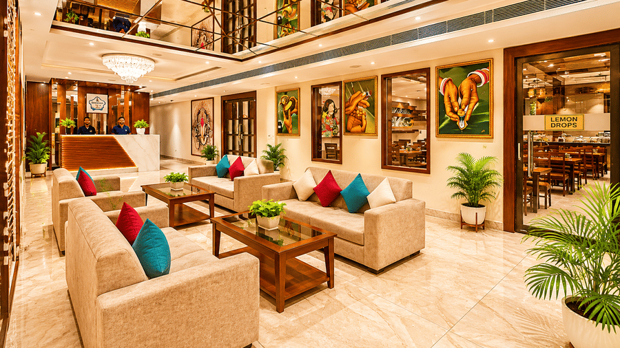 Spacious lobby lounge with sofas, framed artwork and green plants across two levels at Eastlynn Resort, Rishikesh.