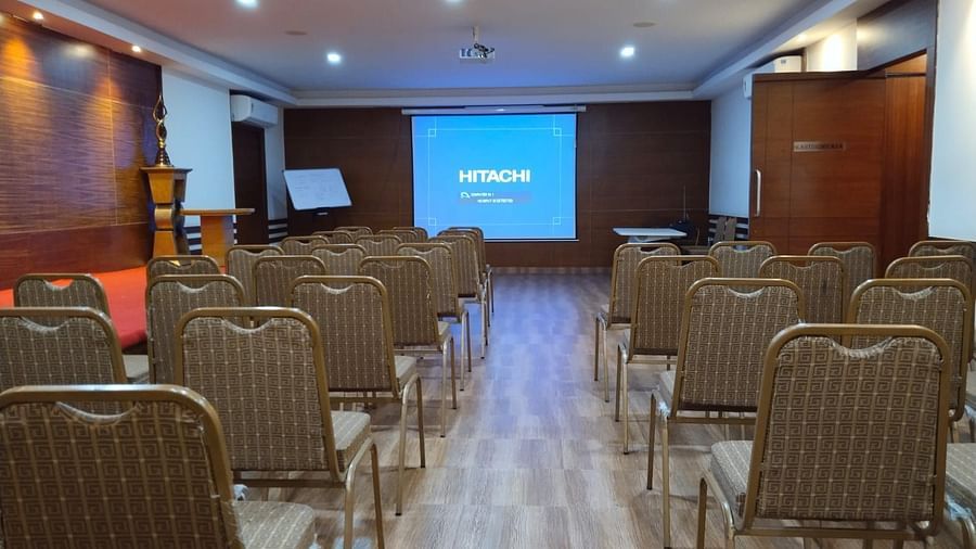 Rear view of a air conditioned conference room with Hitachi pdf open on the projector with a side board placed in the corner at Hotel Dr Rajkumar International.