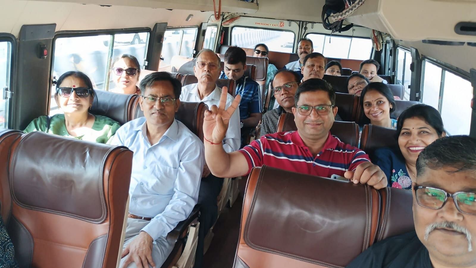 Group of people smiling and posing inside a tempo traveller during a group trip.