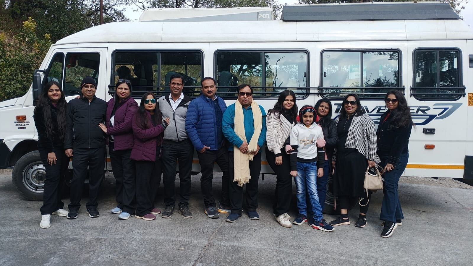 Group of travellers posing together in front of a bus, ready for their trip.