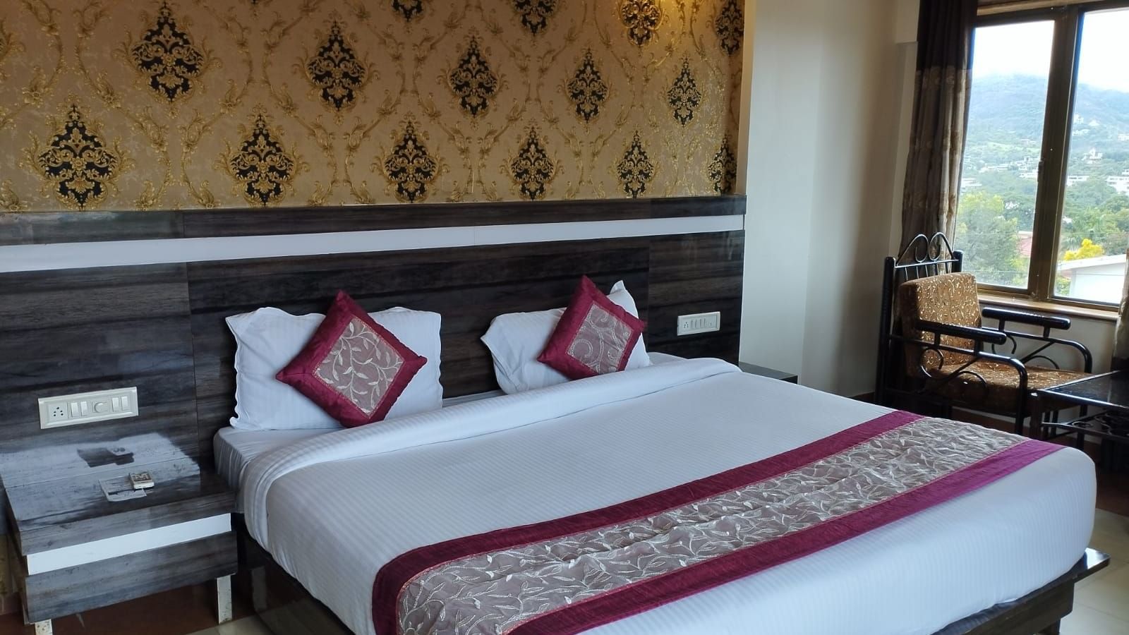 The Super Deluxe Room of Mountview Resort features a king size bed, bedside tables, and a seating area beside the glass windows that offer views of the natural surroundings.