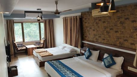 The Suite at Mountview Resort, furnished with two king size beds, a wall-mounted TV, air-conditioning, and a seating area with windows that open to the natural setting outside.