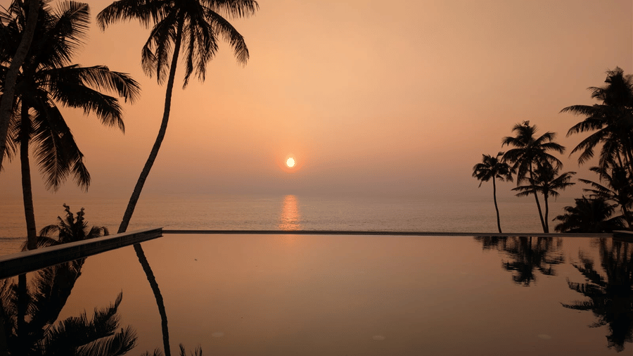 Rooftop infinity pool at SUKAVI during sunset with the pool edge overlooking the horizon and the sky visible in the background.
