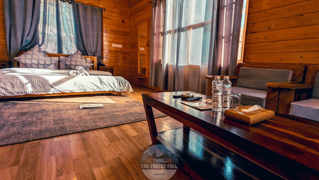 A Deluxe Room at Dawat e Drung by FrozenFall Resort, Drung, Tangmarg, showing a wooden coffee table, 1 double bed and curtains on the windows.