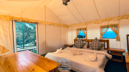 A Luxury Tent at Dawat e Drung by FrozenFall Resort, Drung, Tangmarg, featuring a double bed, wooden walls, a ceiling fan and window curtains.