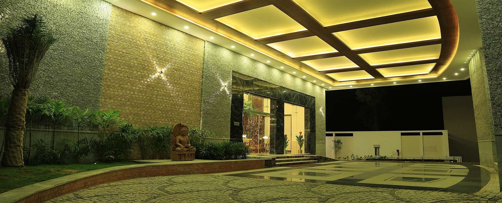Well-lit entrance of Dhanalaksmi Srinivasan Hotels, Perambanur with a pathway leading to the door.