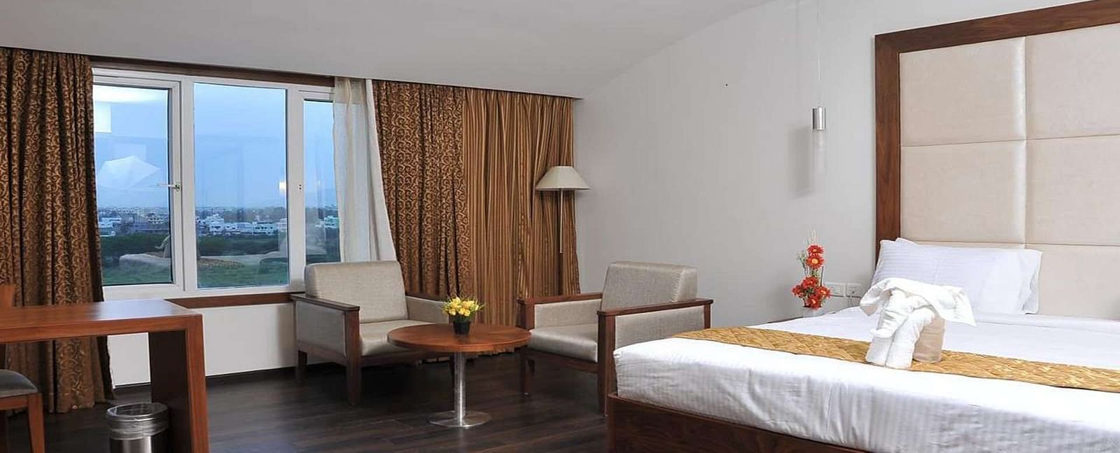 Executive Room with a king size bed, a chair, and a partially visible window at Dhanalaksmi Srinivasan Hotels, Perambalur