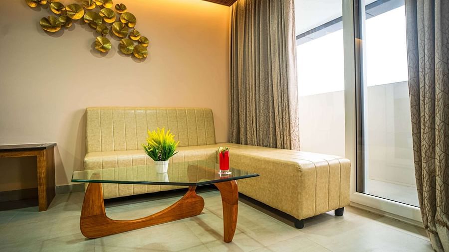 A bright seating area at Mansha Palace includes a modern glass table, a comfortable sofa, and balcony access.