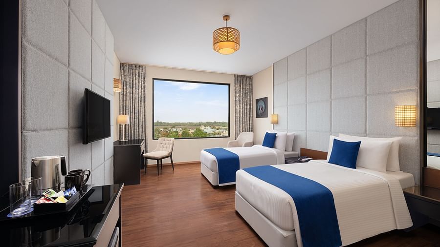Deluxe Twin Room at Essentia Luxury Hotel, Indore with twin beds, a television and a work desk and chair