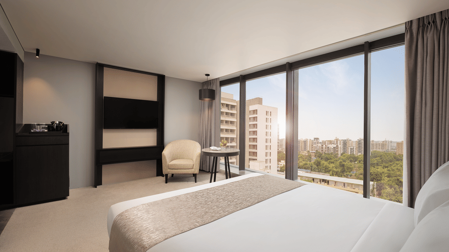 Premier Room with a king size bed facing the TV on the wall and a large window with a view at Essentia Premier, offering the best place to stay in Pune