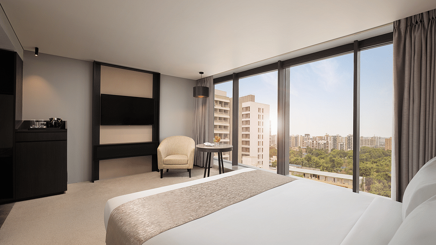 Premier Room with a king size bed and a view through a large window at Essentia Premiere, Pune.