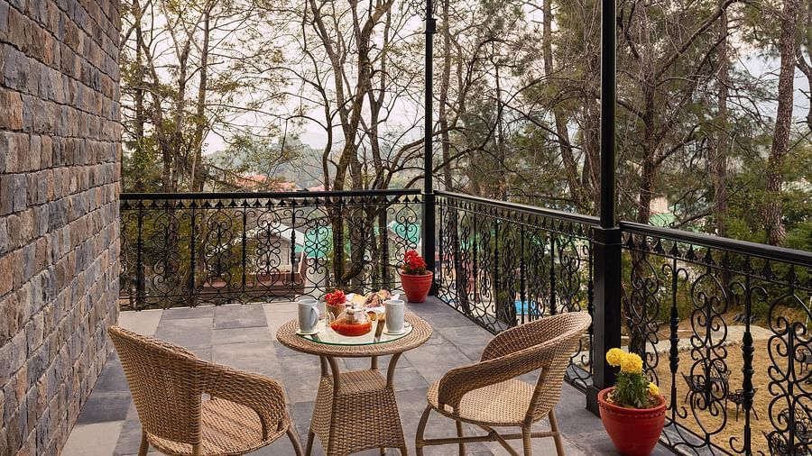 A coffee table and chairs in a balcony at INFINITEA Dak Bungalow, Palampur