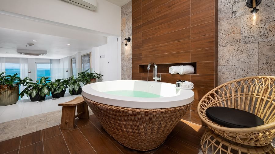 A bathtub in an ambiently lit bathroom in our suite - S Hotel Montego Bay, Jamaica