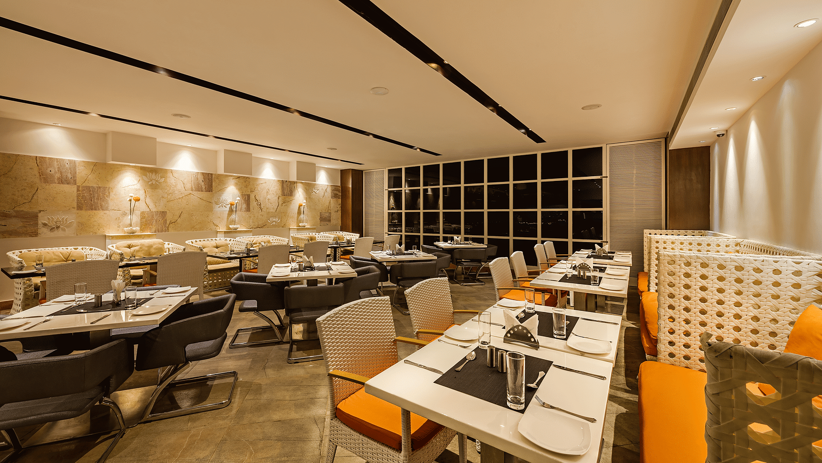 Warm and inviting restaurant dining area with patterned chairs, beige sofas and a neutral color palette - TGI Grand Fortuna, Hosur