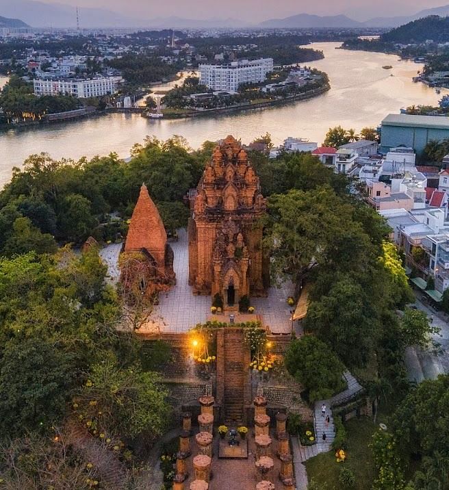An aerial of a monumental structure covered with trees ans has a small river flowing behind it -  Alibu Resort Nha Thrang