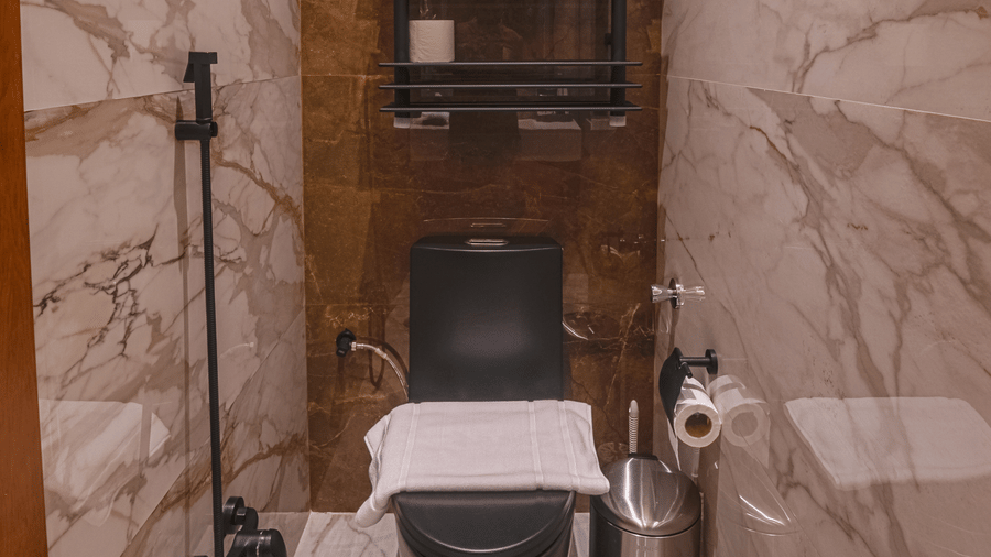 Bathroom in the Standard Twin Rooms at Grand Iva Hotel, Abha, featuring a western commode, towel rack, and bathroom fittings.
