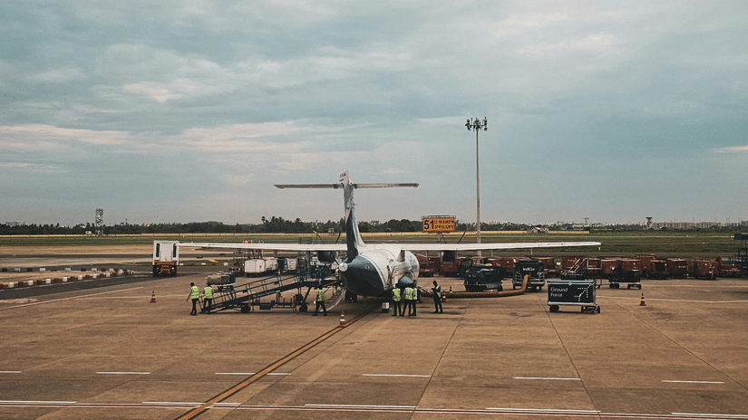An airplane is parked on an airport tarmac under a cloudy sky.