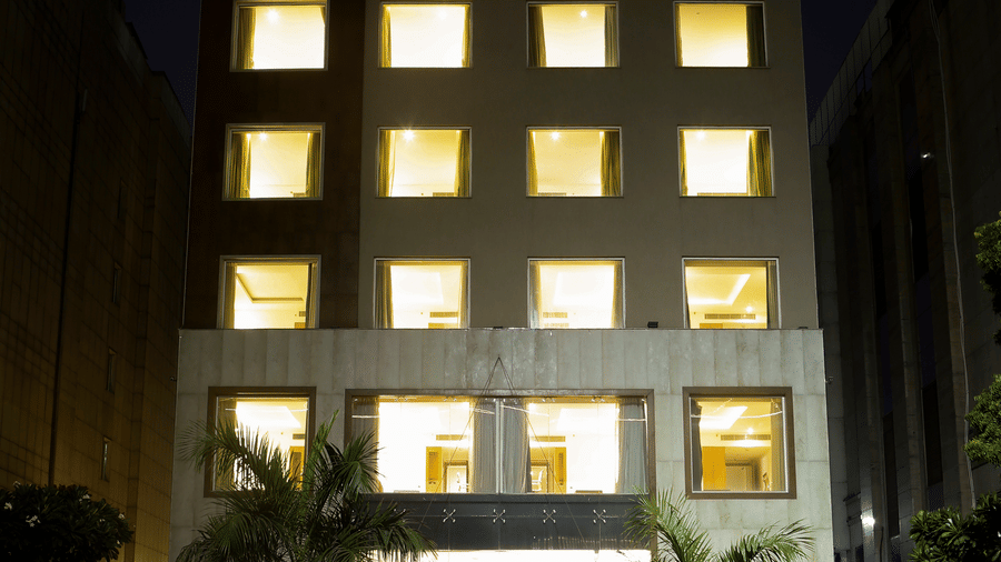 A multi-story hotel building illuminated at night with a glowing pink sign at the top.