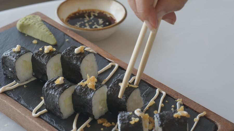 Close-up of a hand placing hors d’oeuvres on a wooden serving tray - Mayfair Cafe & Suites, Dalhousie