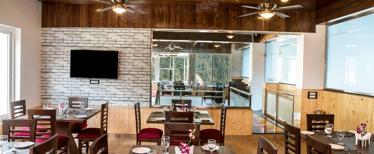 Front view shot of the dining area with a shiny wooden ceiling at Regenta Inn DLS.