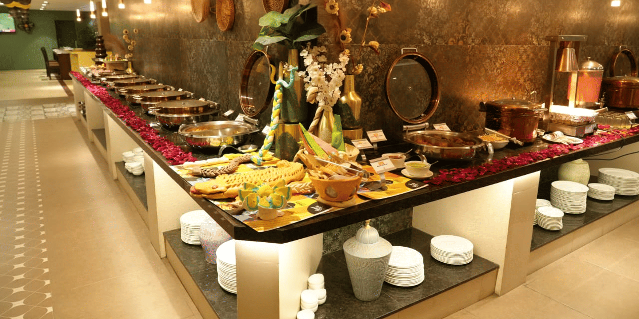 Lavish buffet setup at The Papaya Kitchen, Papaya Tree Hotels,  featuring a wide variety of dishes displayed in an elegant, modern dining space.