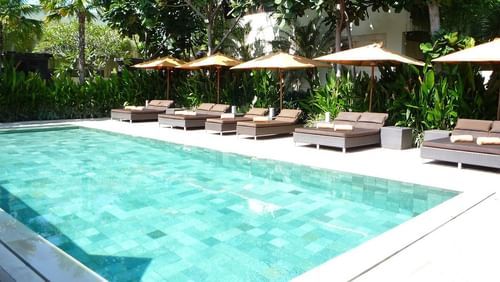 sun loungers and umbrellas beside a swimming pool during the day