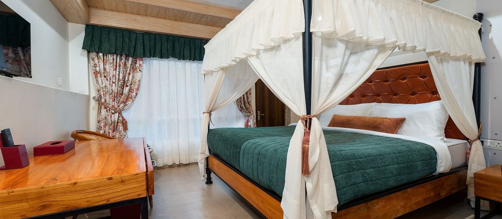 Deluxe room featuring a large bed and wooden furniture accents