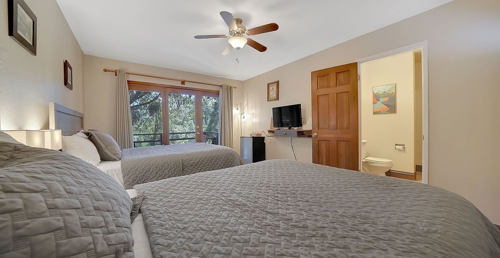 A view of a room at Narrow Gauge Inn with twin beds and a television.