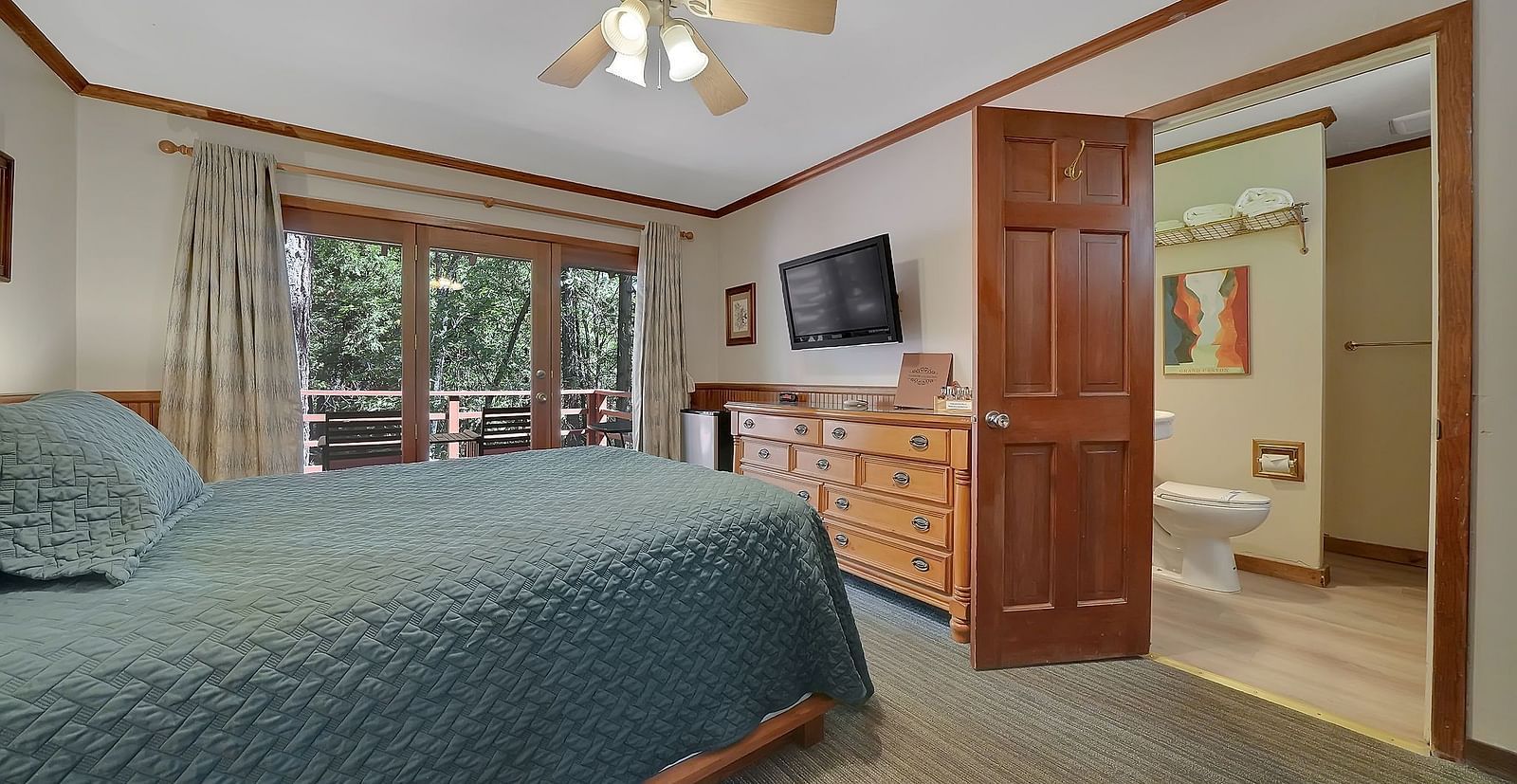 A view of a room at Narrow Gauge Inn with a double bed and sliding doors opening to a balcony.