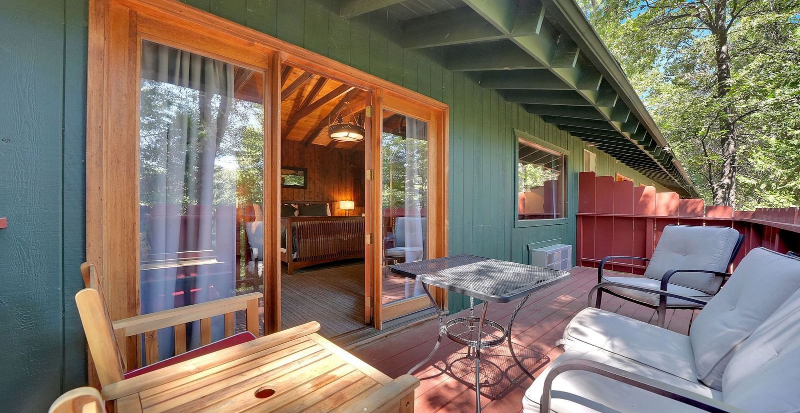 A view of the outdoor patio area o a cabin with sofa seating and a coffee table - Narrow Gauge Inn - A Serenite Hotel Near Fish Camp.