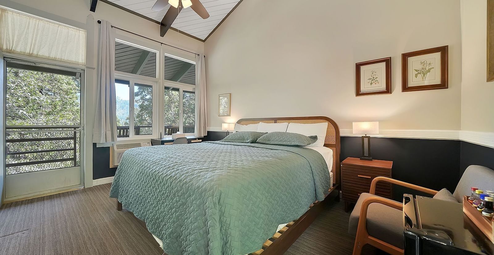 A view of a room at Narrow Gauge Inn with a double bed and sliding doors opening to a balcony.