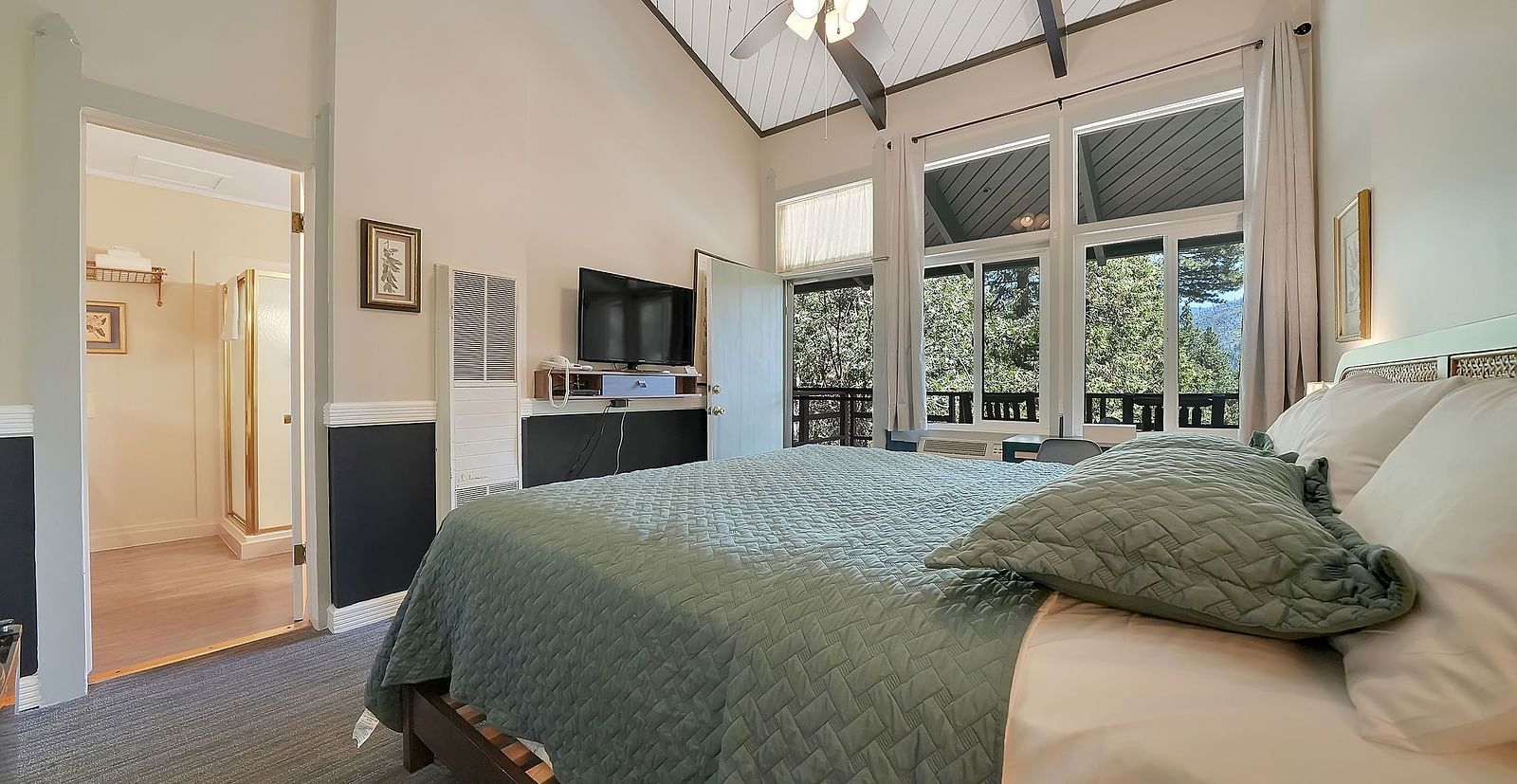 A view of a room at Narrow Gauge Inn with a double bed and sliding doors opening to a balcony.