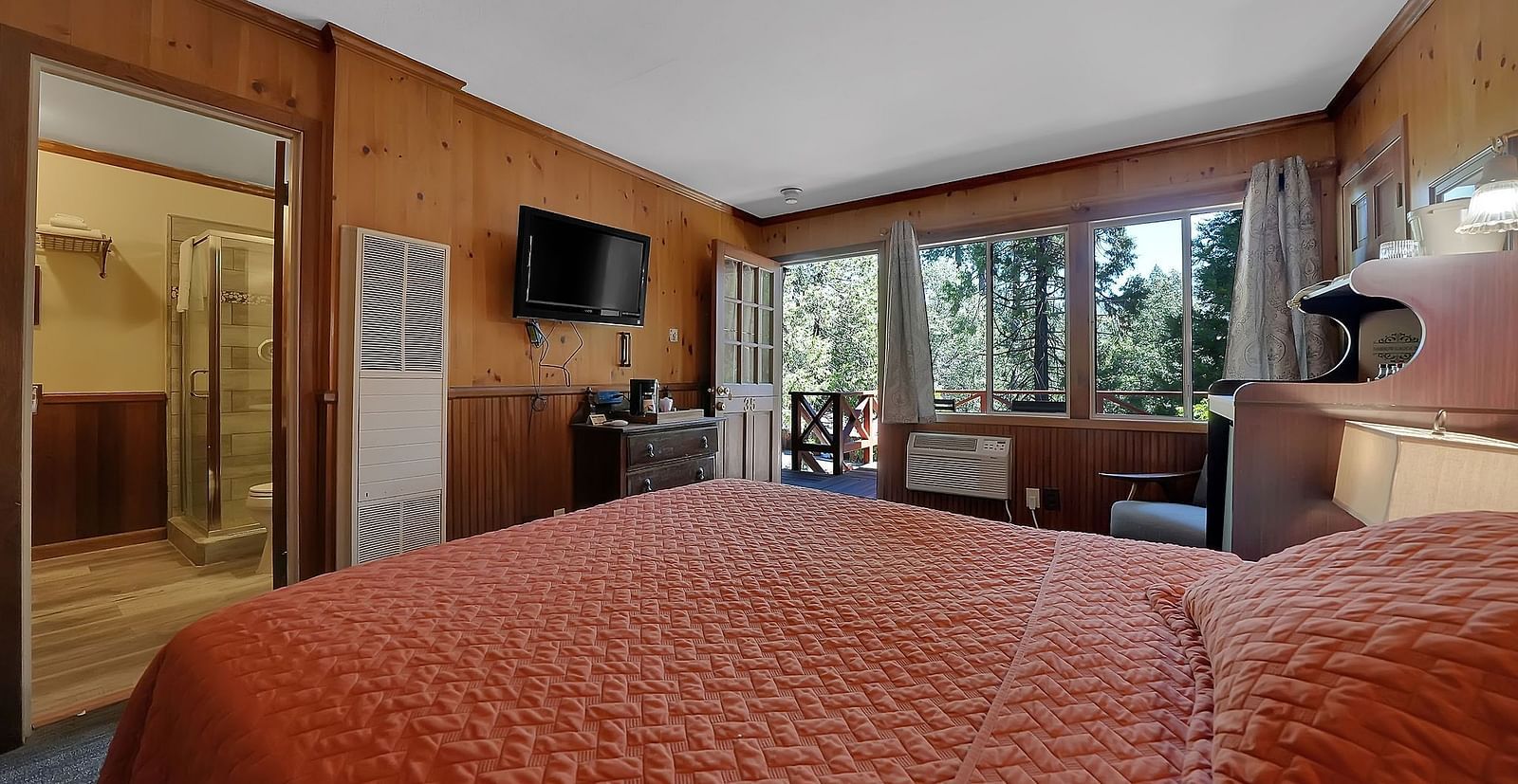 A view of a room at Narrow Gauge Inn with a double bed and sliding doors opening to a balcony.