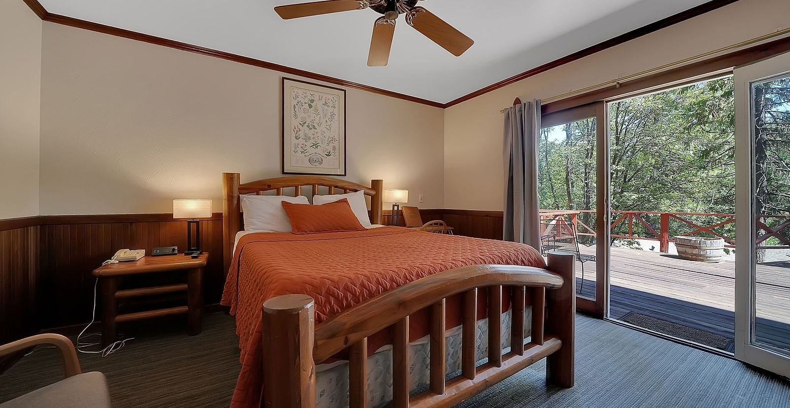 A view of a room at Narrow Gauge Inn with a double bed and sliding doors opening to a balcony.