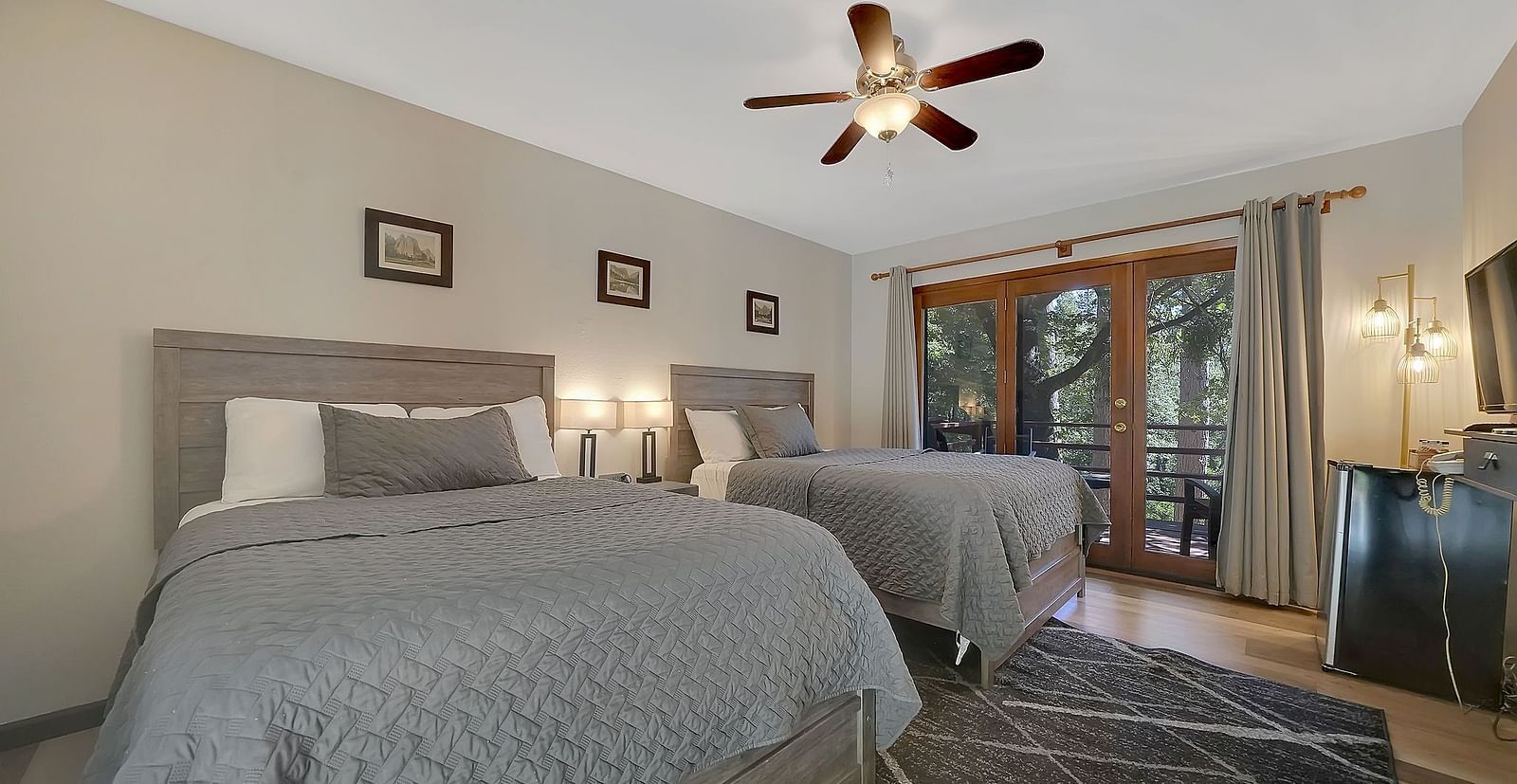 A view of a room at Narrow Gauge Inn with twin beds and sliding doors opening to a balcony.