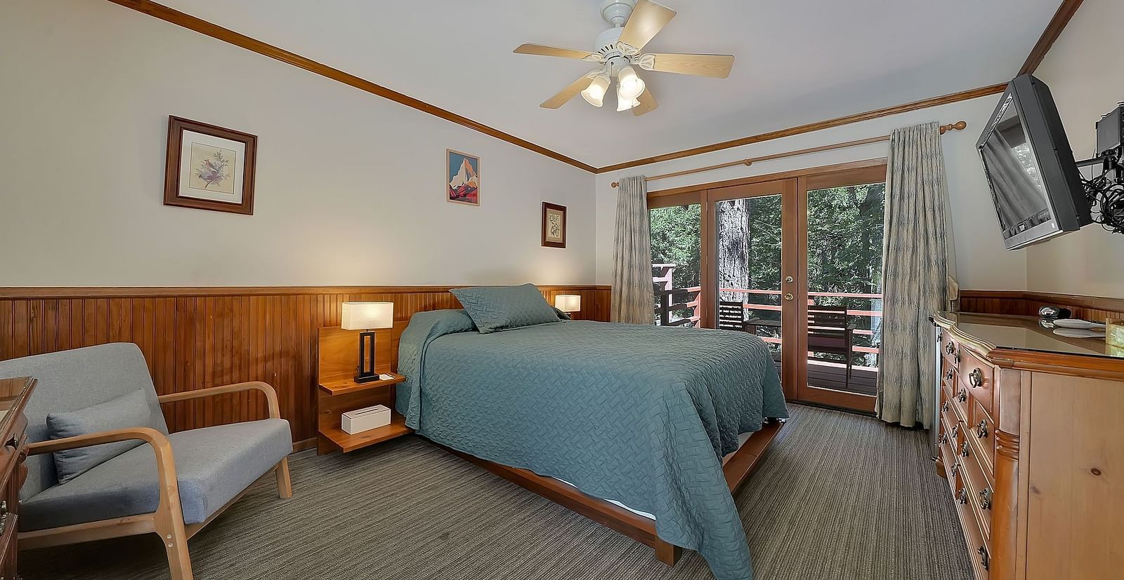 A view of a room at Narrow Gauge Inn with a double bed and sliding doors opening to a balcony.