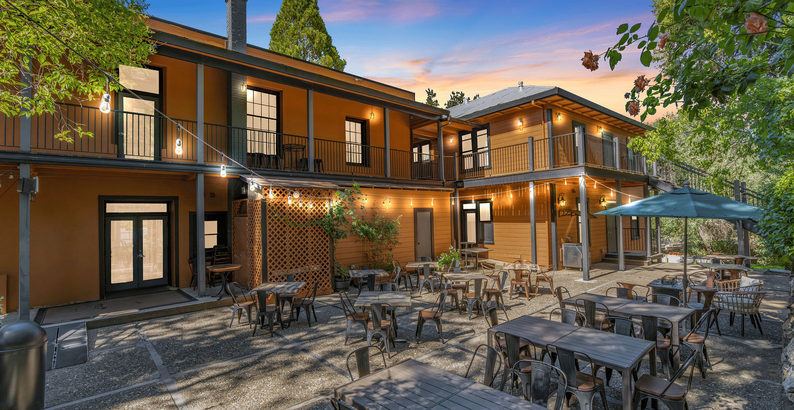 early evening view of the backyard of The Groveland Hotel with tables and chairs.