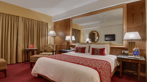 An image of Suite room featuring a double size bed, bedside table with lamp on either side, and a sitting area with sofa chair at Pride Sun Village Resort and Spa, Goa