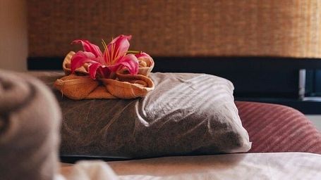 Bed with pillows and flower arrangement in a room at Karma Chalets.
