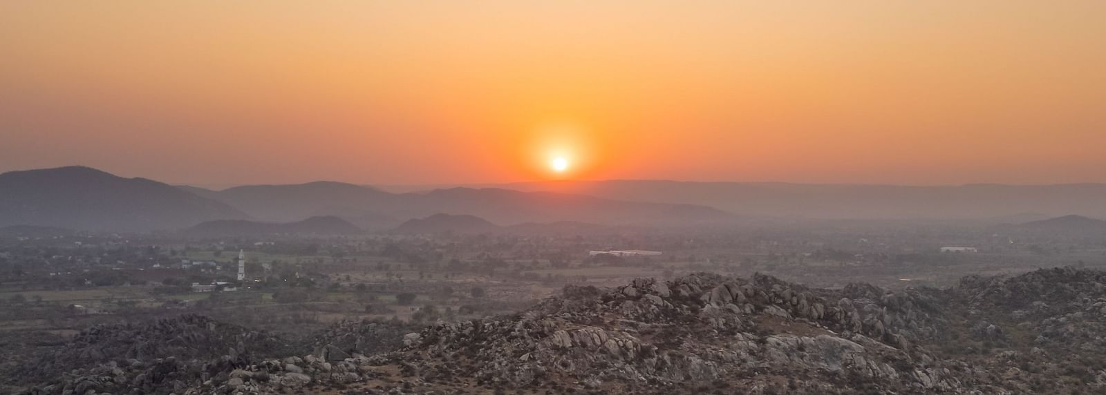 An aerial image of the landscape around Utsav Camp Sariska with the backdrop of a sunset