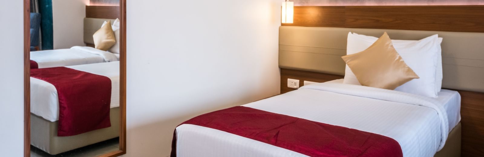  A well appointed hotel room featuring a single bed, a full length mirror, and a modern headboard at Shilton Dee Cee.